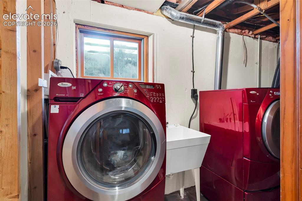 Image 26 of 49: Dedicated laundry area featuring a utility sink, a front-loading washer, an