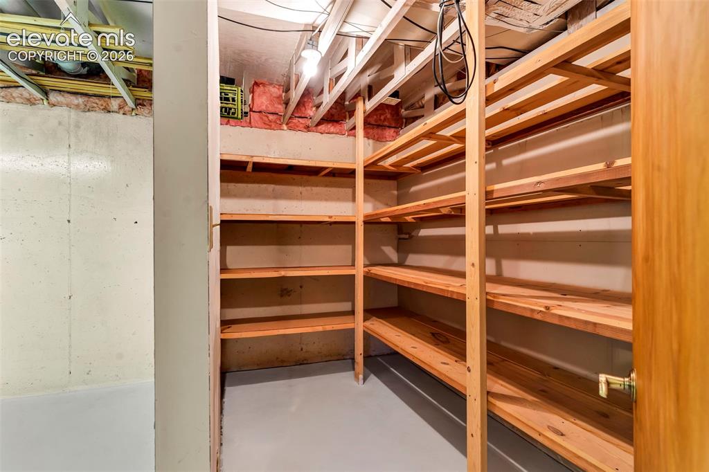 Image 27 of 49: Utility room featuring extensive built-in wooden shelving, exposed ceiling