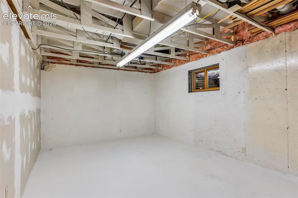 Image 28 of 49: Unfinished basement space featuring exposed ceiling joists, concrete walls,