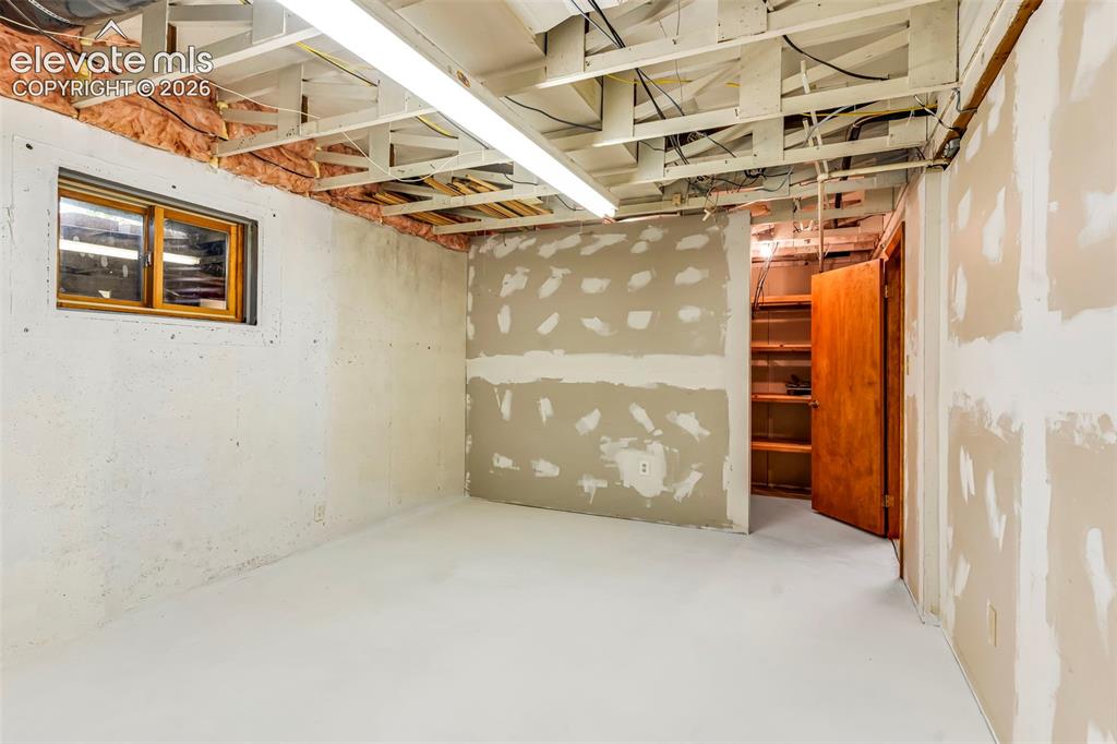 Image 29 of 49: Unfinished basement space featuring exposed ceiling joists, visible insulat