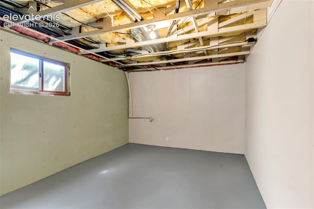 Image 30 of 49: Open basement space featuring a single window, exposed ceiling joists, and