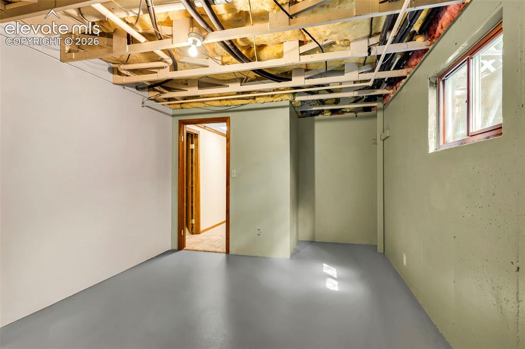 Image 31 of 49: Basement area featuring a painted concrete floor, exposed ceiling joists wi