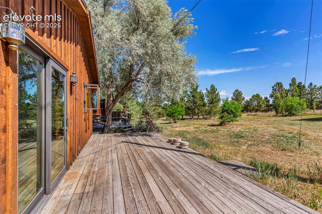 Image 32 of 49: Expansive wood deck with a natural finish, featuring double-pane glass door