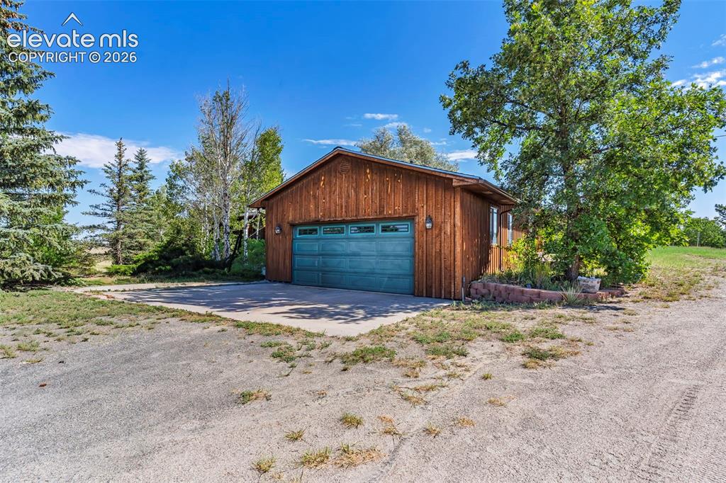 Image 4 of 49: Detached garage featuring wood siding, a double garage door, concrete drive