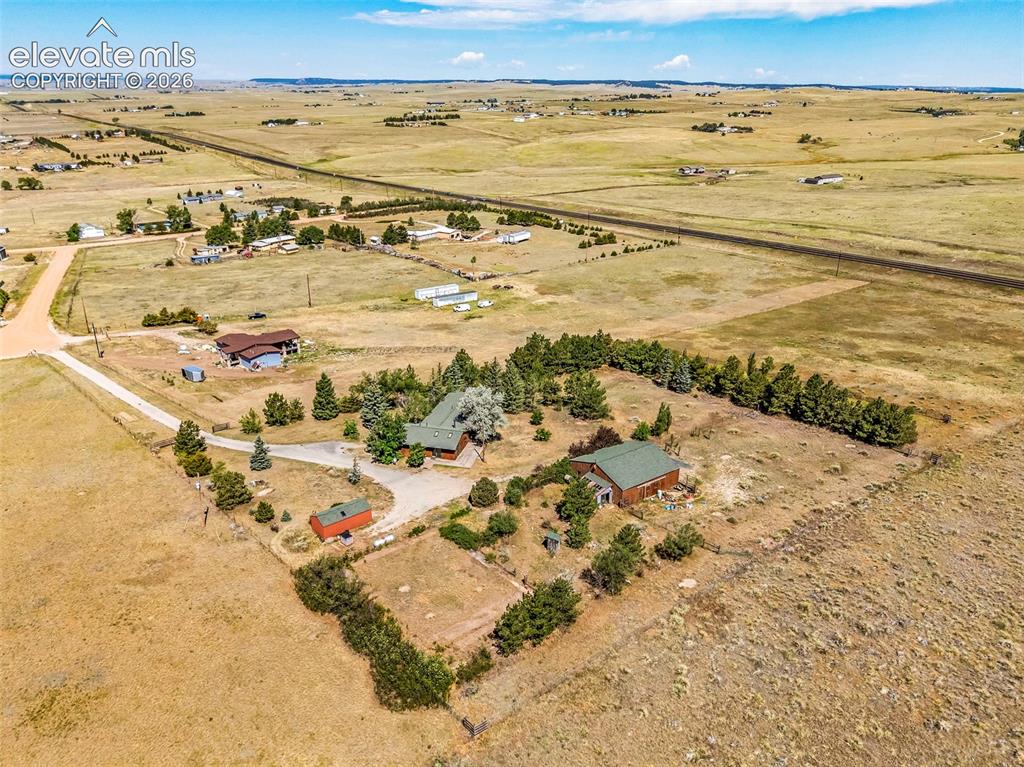 Image 45 of 49: Aerial property overview featuring two residential structures with green ro