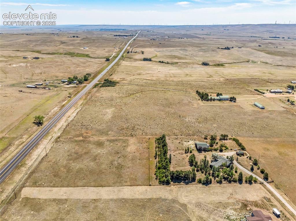 Image 49 of 49: Expansive rural property featuring a main residence with a dark roof and su