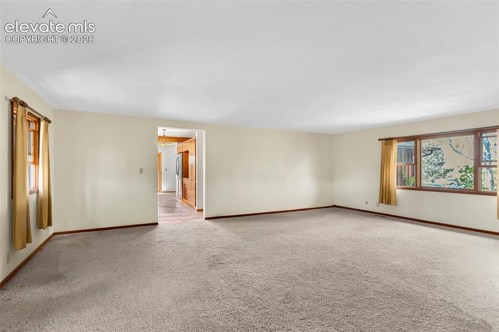 Image 6 of 49: Spacious living area featuring neutral carpeting, light-toned walls, and wo