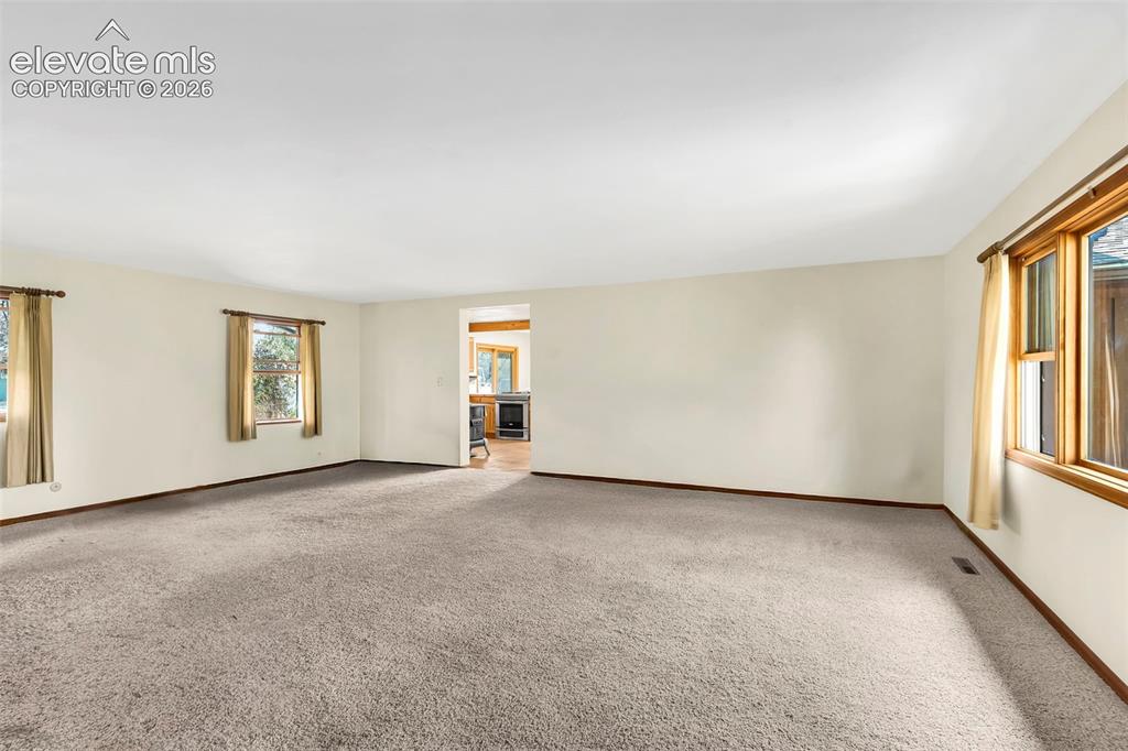 Image 7 of 49: Spacious room with light-toned walls and neutral carpeting