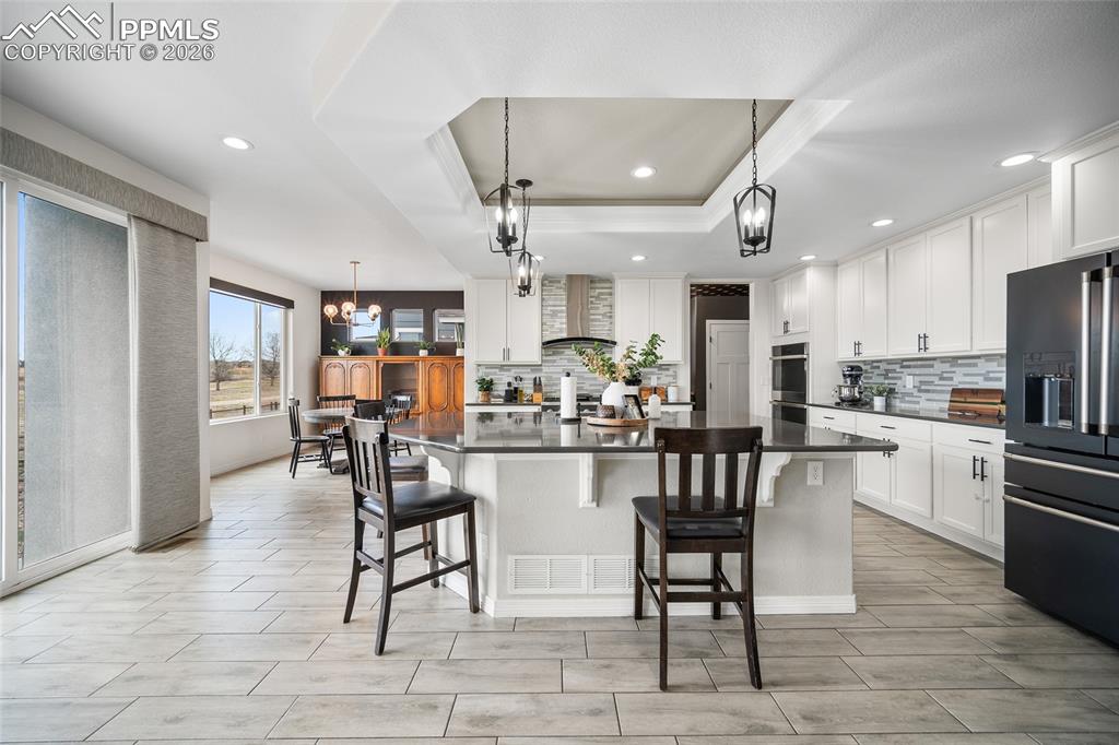 Image 13 of 50: Kitchen featuring grey quartz countertops, decorative backsplash, black ref