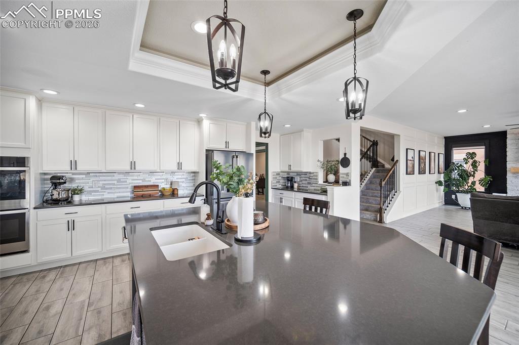 Image 16 of 50: Kitchen with a sink, a kitchen island with sink, a tray ceiling, stainless