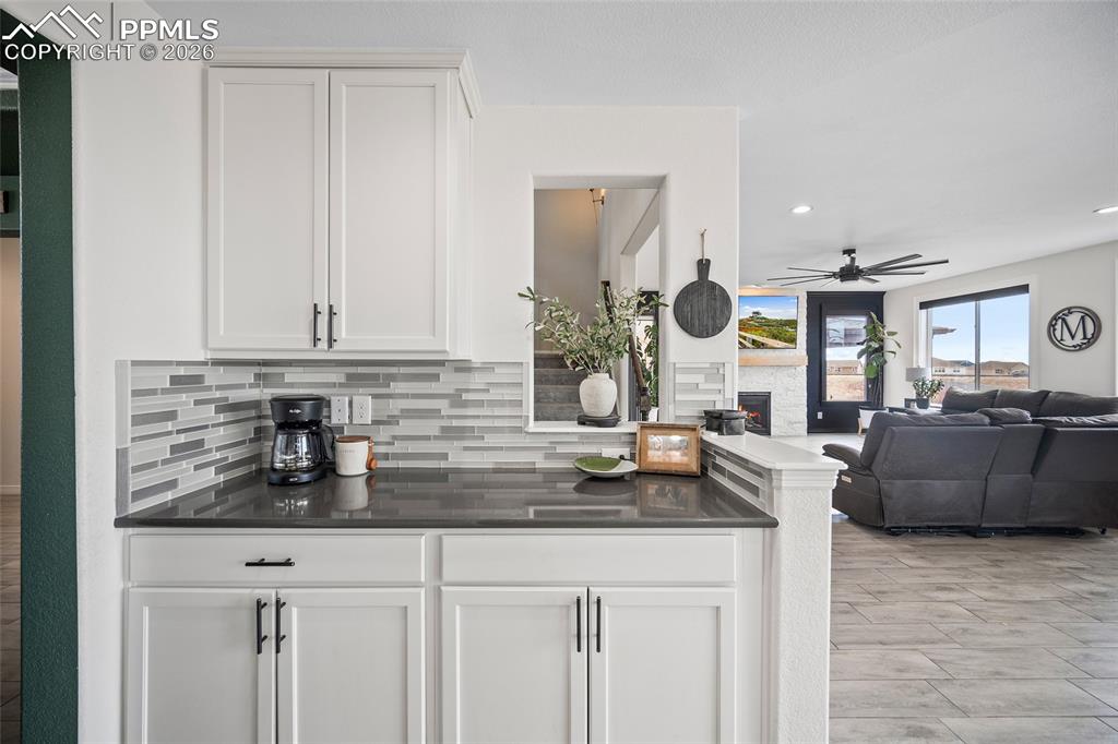Image 20 of 50: Bar featuring recessed lighting, ceiling fan, a warm lit fireplace, and dec