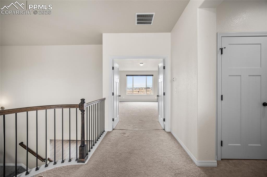 Image 25 of 50: Hall featuring an upstairs landing, visible vents, baseboards, and carpet f