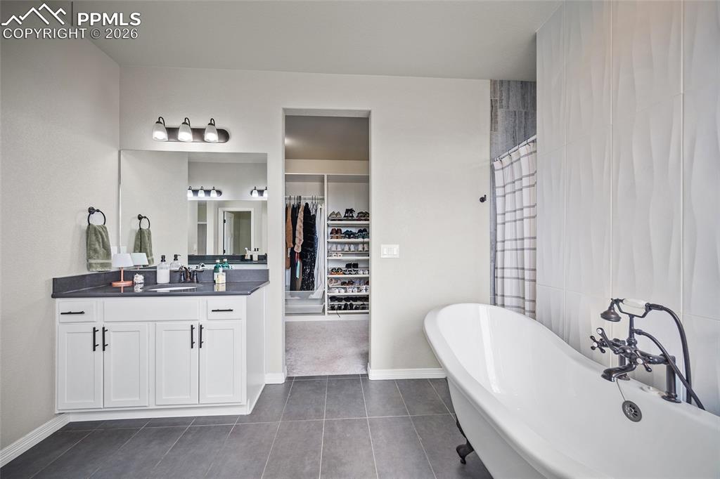 Image 29 of 50: Full bathroom featuring a freestanding bath, a spacious closet, vanity, til