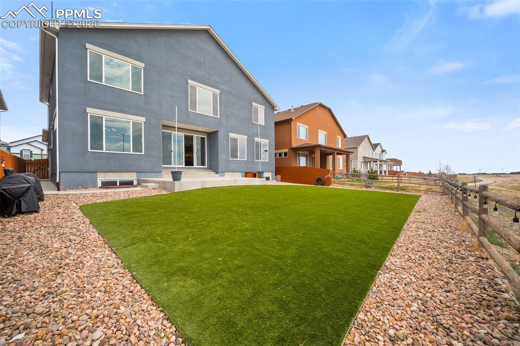 Image 43 of 50: Rear view of house with a patio area, a fenced backyard, and turf lawn