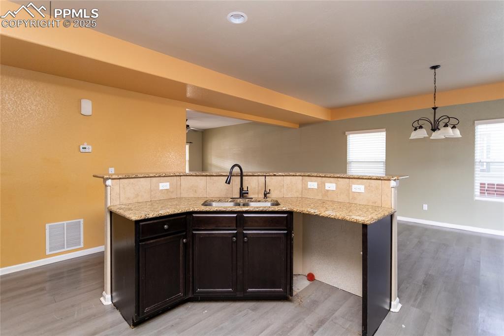 Image 13 of 49: Kitchen featuring a center island with sink, hanging light fixtures, light