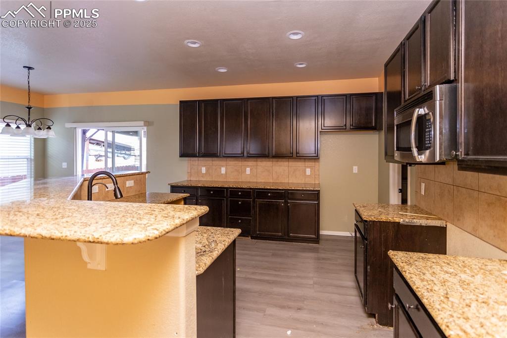 Image 14 of 49: Kitchen with decorative backsplash, dark brown cabinets, stainless steel mi