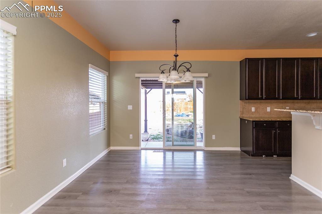 Image 17 of 49: Unfurnished dining area with a chandelier and light wood-type flooring