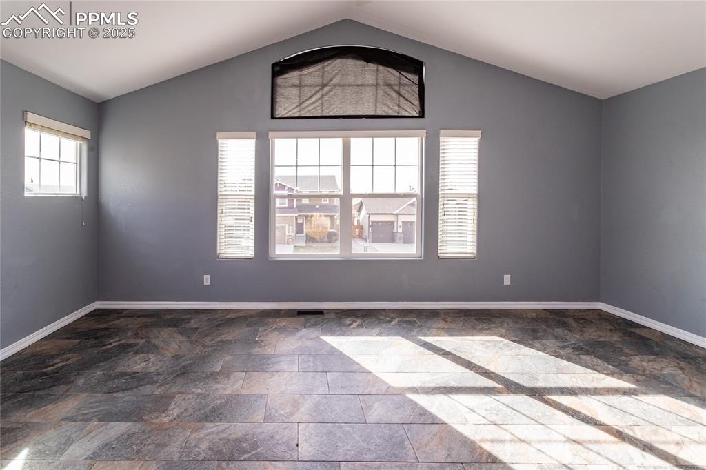 Image 20 of 49: Primary bedroom featuring vaulted ceiling and dark stone finish flooring