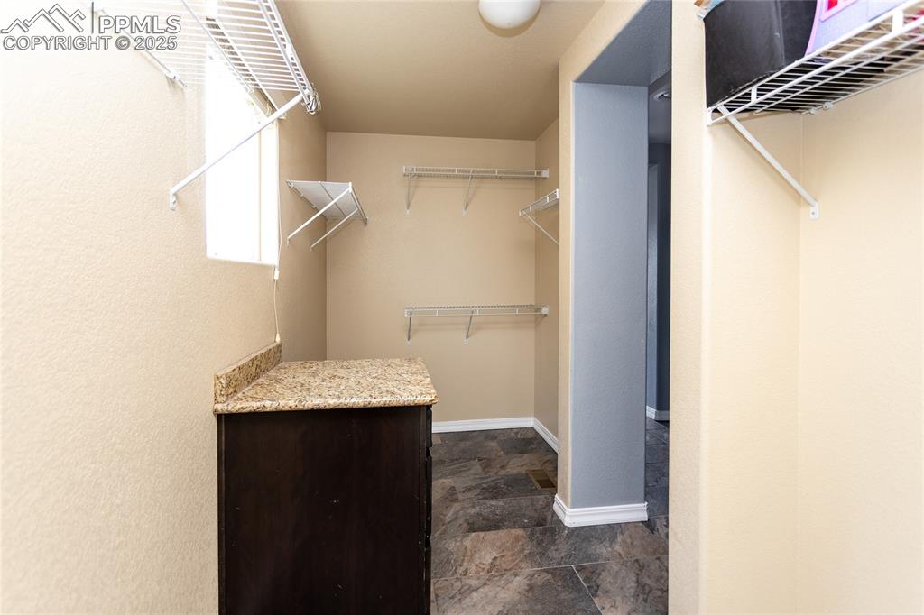 Image 23 of 49: Walk in closet with dark stone finish flooring