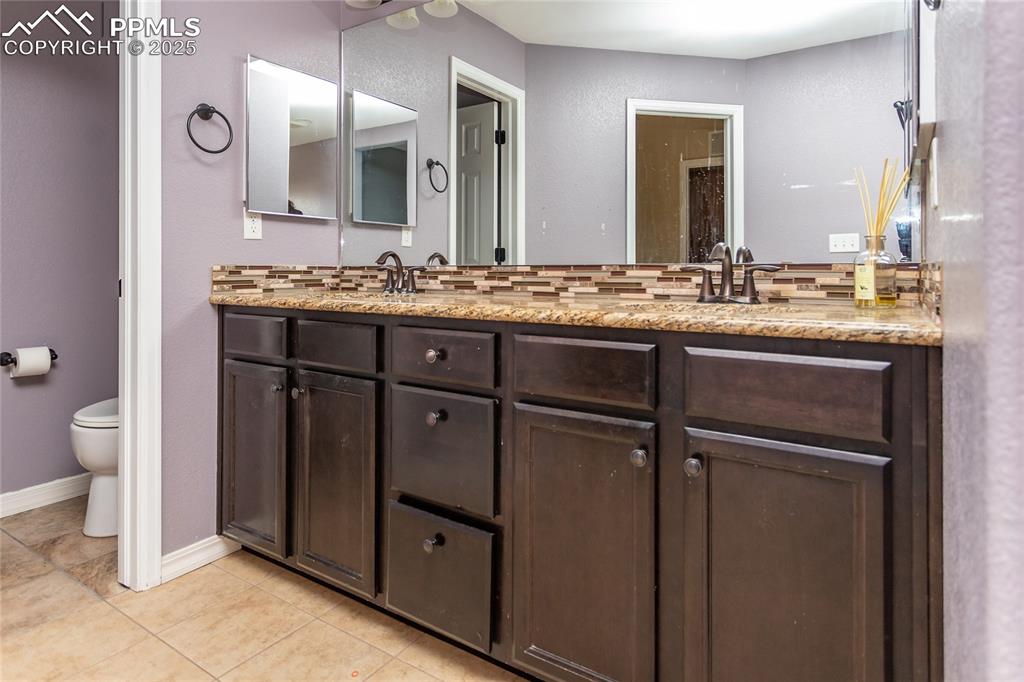Image 25 of 49: Bathroom with double vanity, light tile patterned floors, and decorative ba