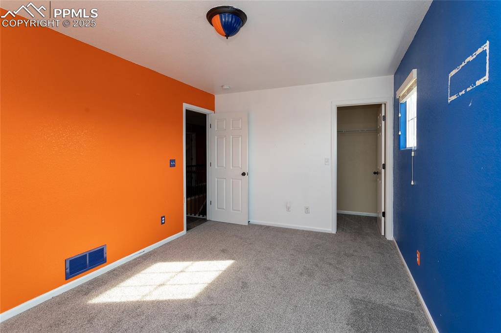 Image 34 of 49: Unfurnished bedroom with a walk in closet and carpet