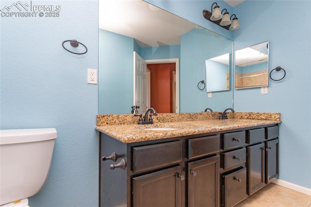 Image 43 of 49: Bathroom with double vanity, a textured wall, and light tile patterned floo