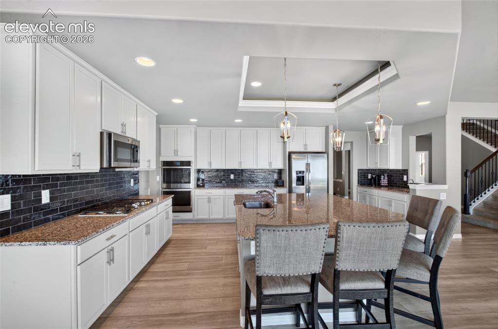 Image 11 of 35: Spacious kitchen featuring white cabinetry, dark brick-patterned backsplash