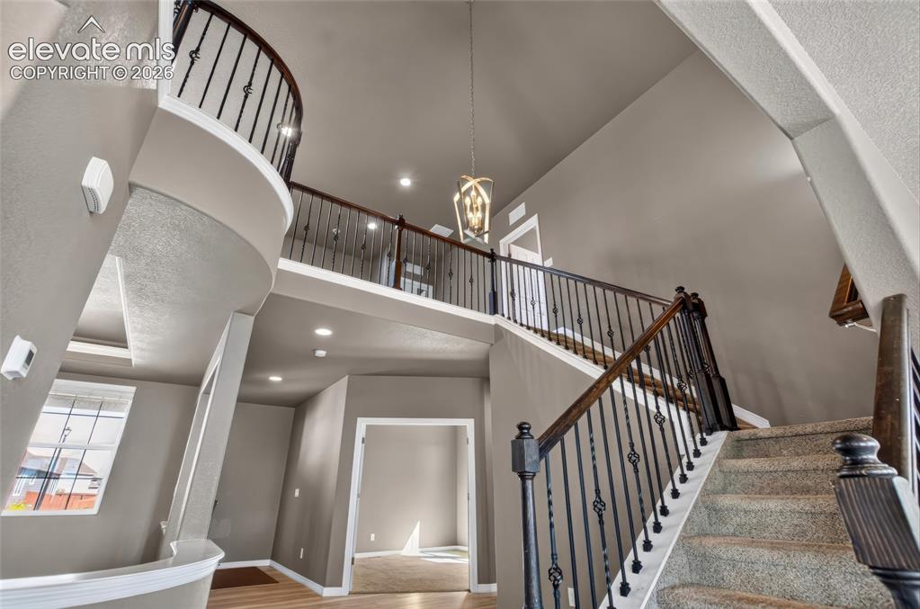 Image 12 of 35: Two-story foyer featuring a curved balcony, carpeted staircase with ornate