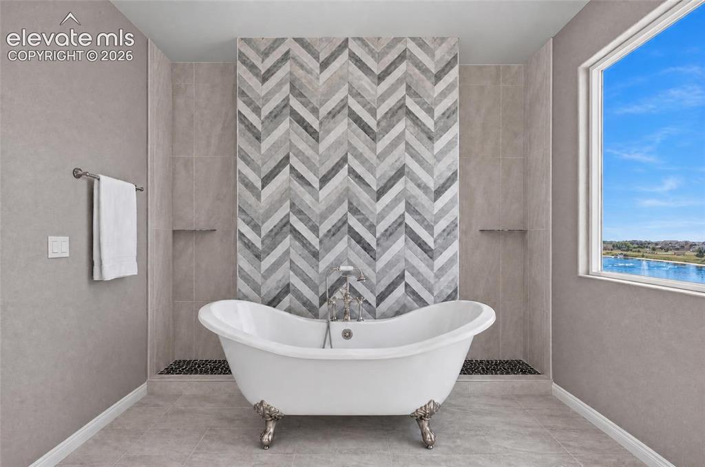 Image 16 of 35: Freestanding clawfoot tub with a chevron-patterned tile accent wall