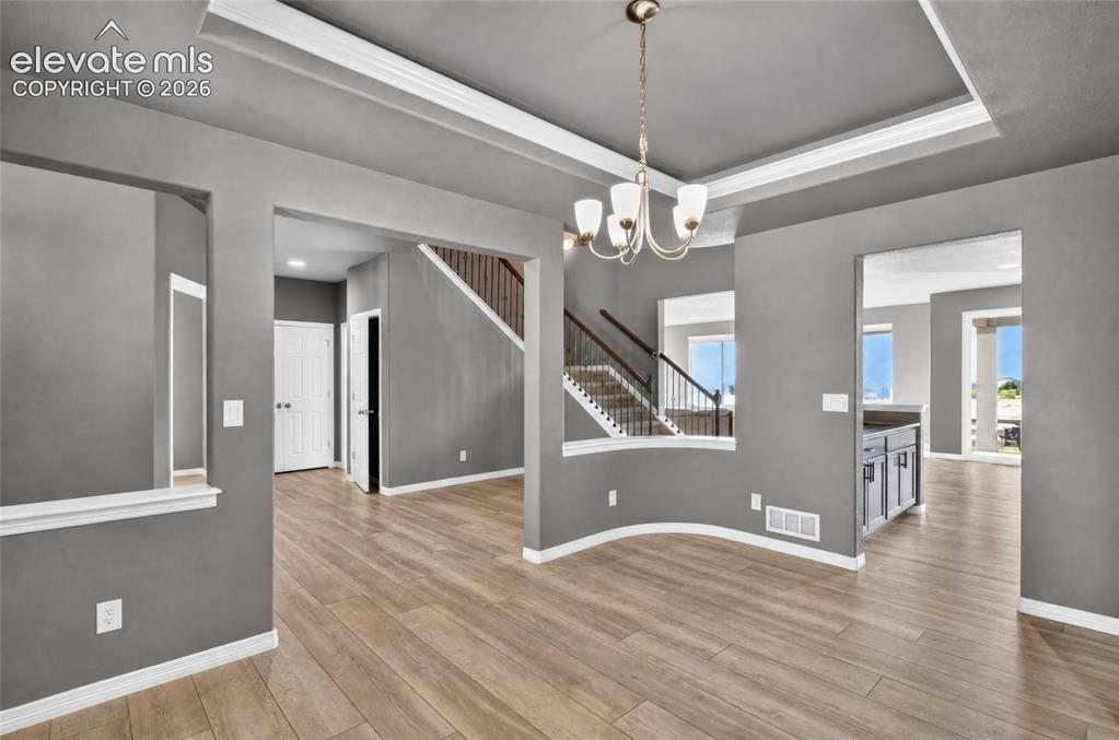 Image 4 of 35: Recessed ceiling with crown molding, elegant chandelier, wood-finish floori