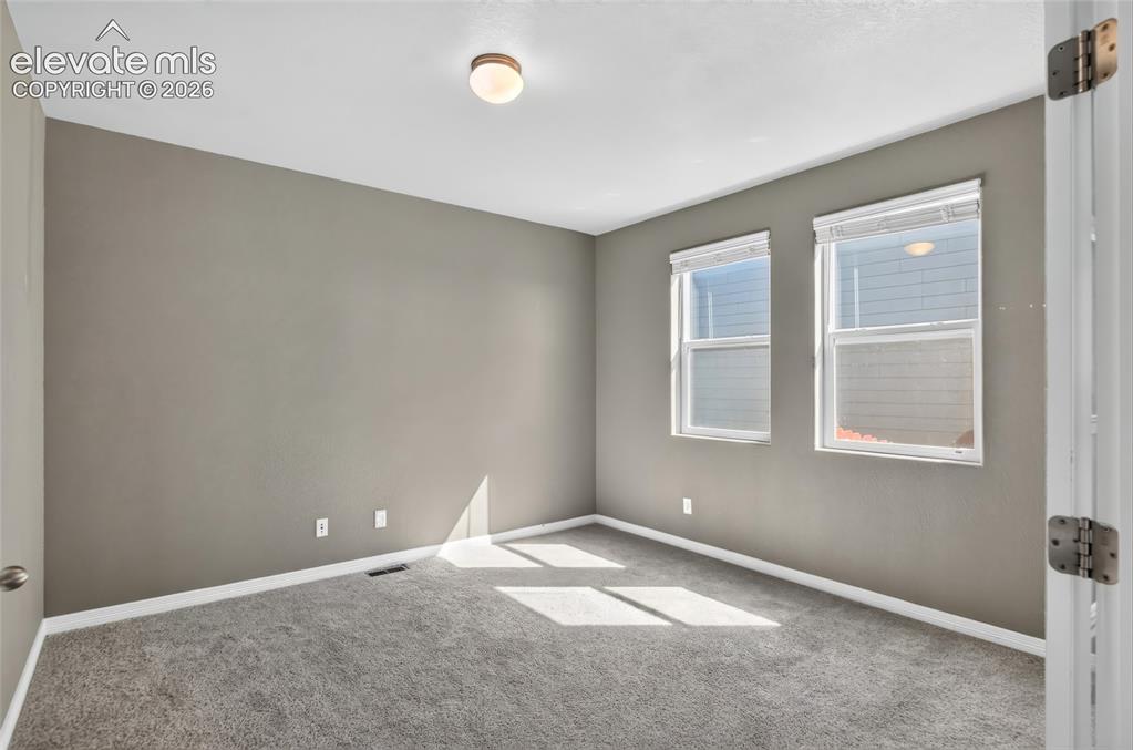 Image 5 of 35: Room featuring two windows, neutral wall paint, and gray carpet flooring