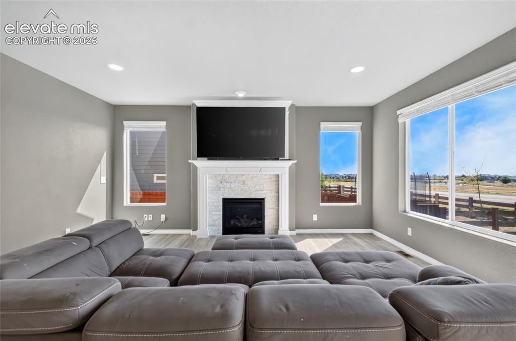 Image 7 of 35: Built-in fireplace with stone surround, wood-finish flooring, recessed ligh
