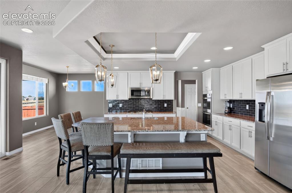 Image 9 of 35: Kitchen featuring a central island with a granite countertop, white cabinet
