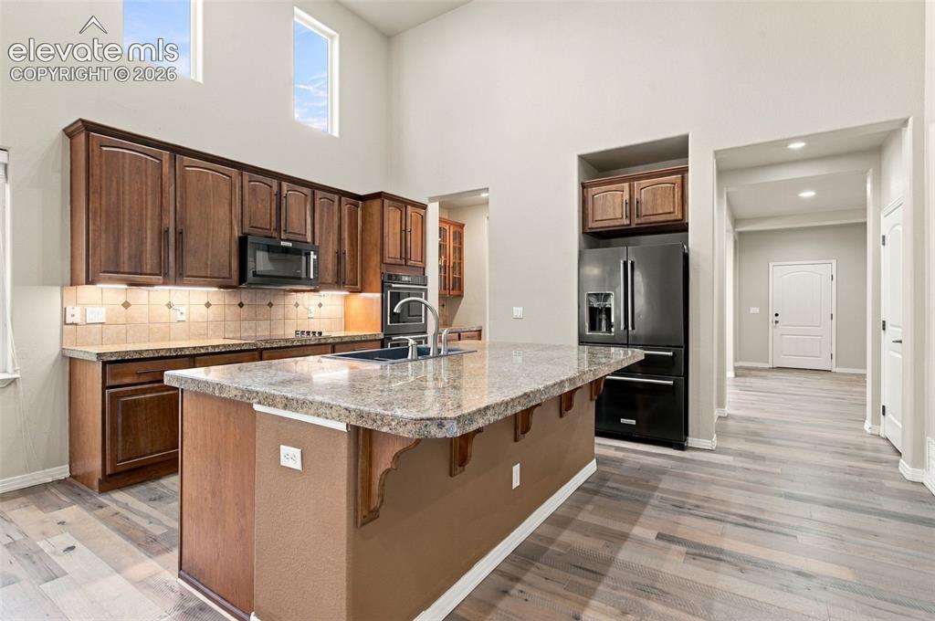 Image 10 of 48: Kitchen featuring wood cabinetry, stone-finish countertops, a central islan