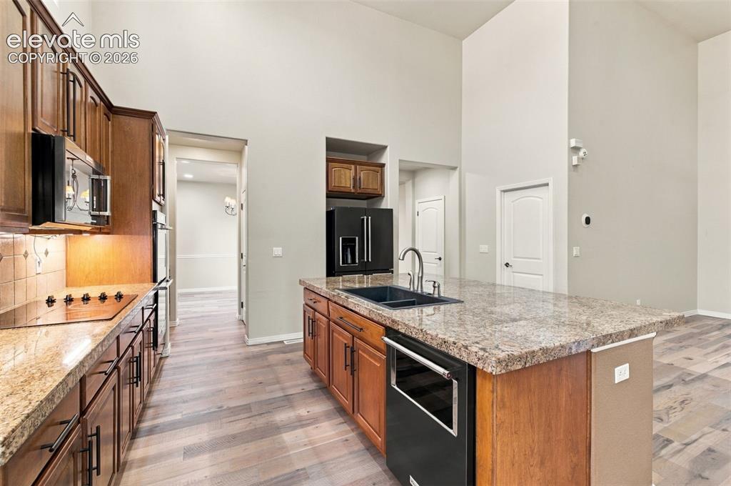 Image 11 of 48: Kitchen featuring wood cabinetry, stone countertops, a center island with a