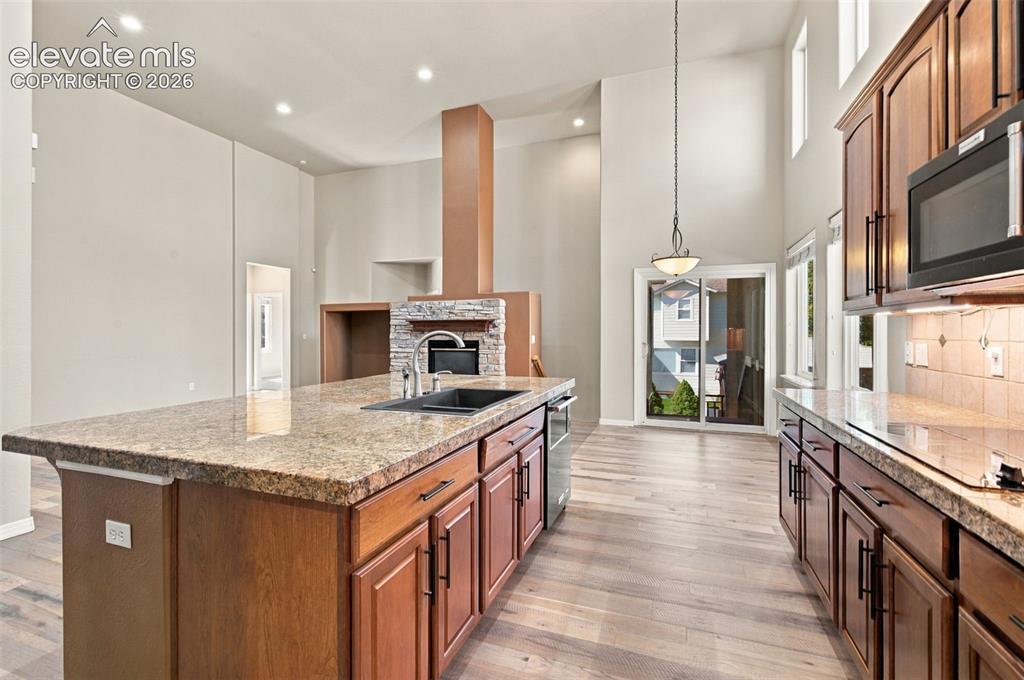 Image 12 of 48: Kitchen featuring a large central island with a stone-finish countertop, un