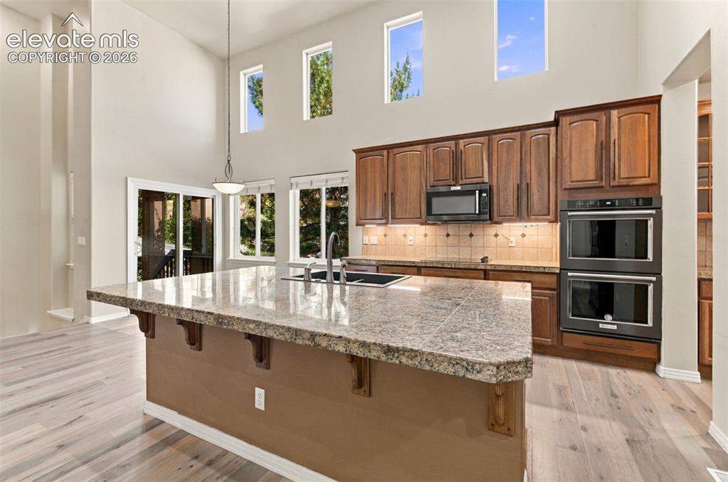 Image 13 of 48: Kitchen featuring vaulted ceilings, oversized center island with stone coun