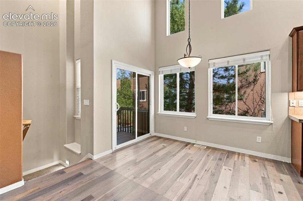 Image 14 of 48: High-ceiling interior featuring wood-finish flooring, sliding glass patio d