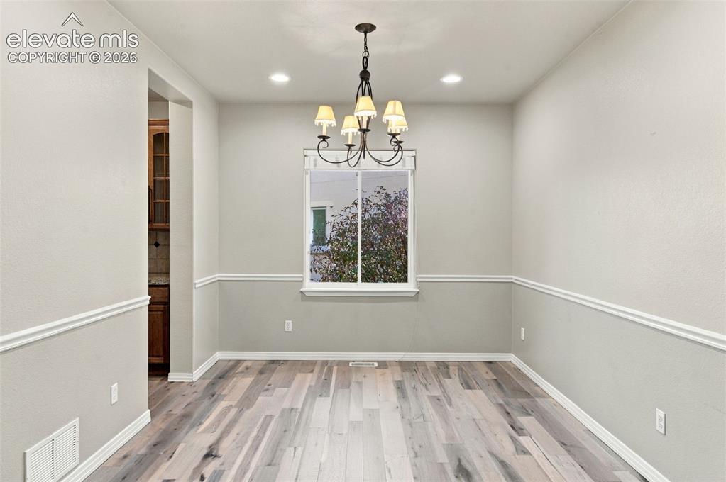 Image 15 of 48: Multi-tone wood-finish flooring, crisp white chair rail molding, and a five