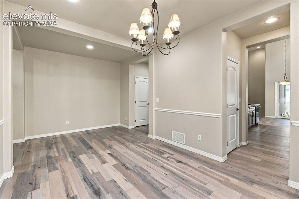 Image 16 of 48: Wood-finish flooring, multi-arm metal chandelier, recessed lighting, and ch
