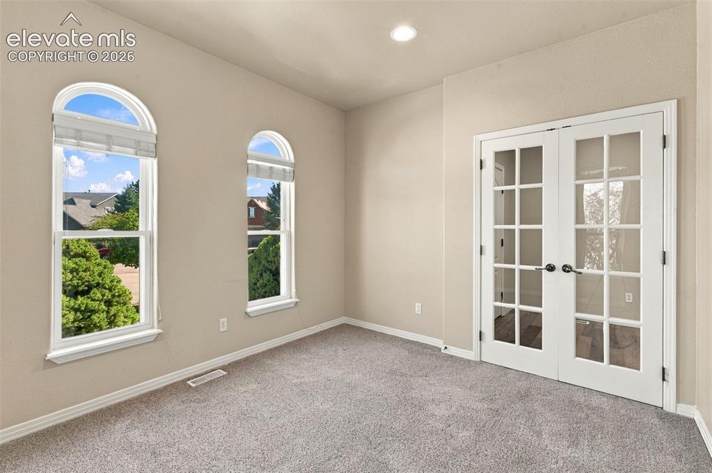 Image 18 of 48: Interior room featuring arched windows, double French doors with glass pane