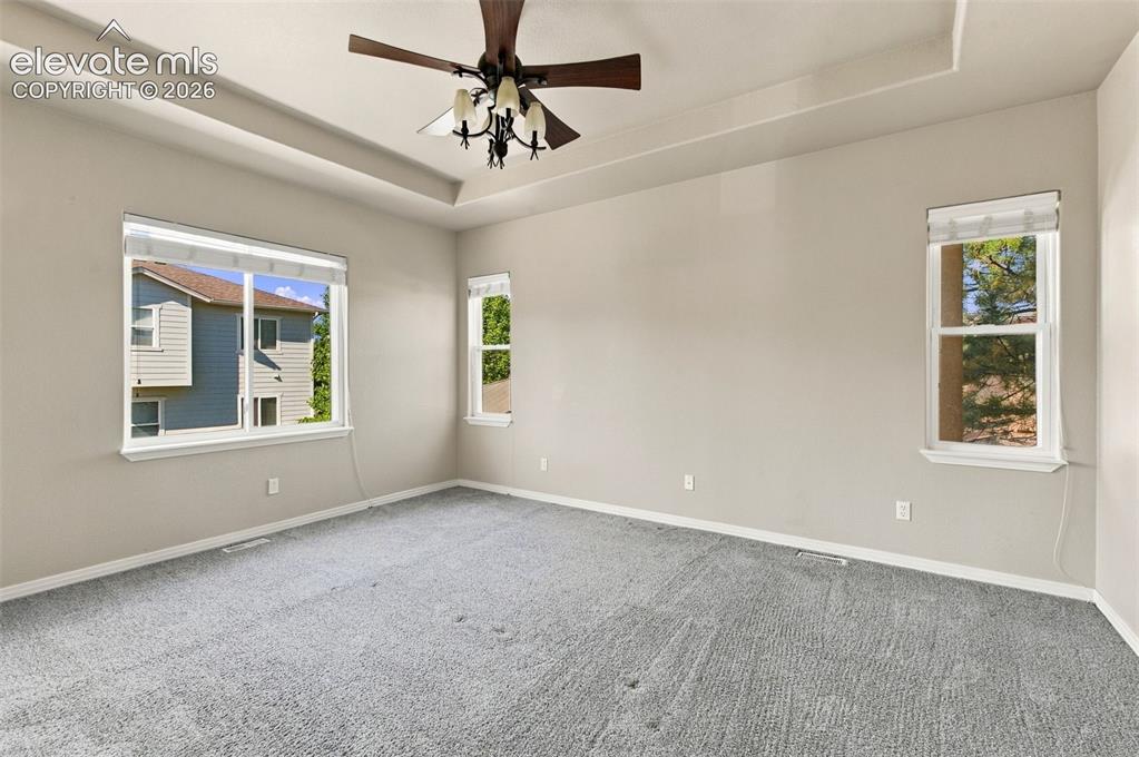 Image 19 of 48: Tray ceiling featuring a central multi-light fan, neutral wall tones, carpe