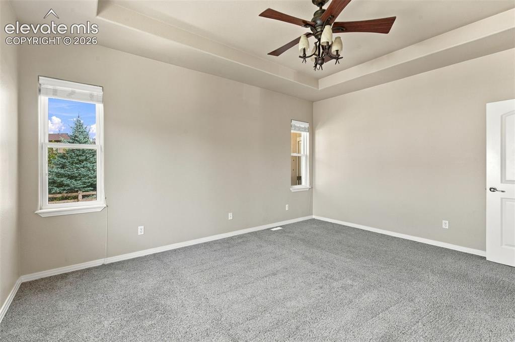 Image 20 of 48: Room featuring a tray ceiling, wall-to-wall carpeting, and a multi-light ce