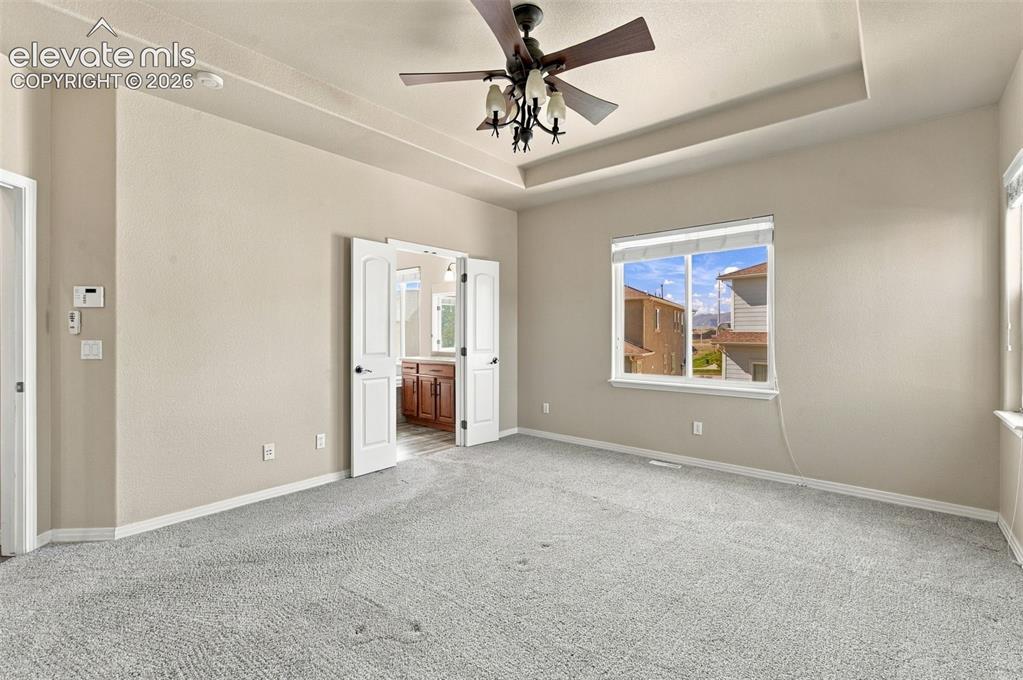 Image 22 of 48: Tray ceiling with a central multi-light ceiling fan, wall-to-wall carpeting