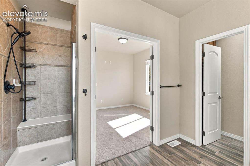 Image 24 of 48: Walk-in shower featuring tiled walls with a built-in bench, matte black plu