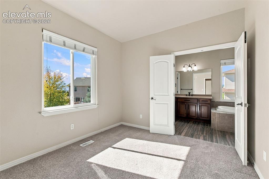 Image 26 of 48: Neutral wall-to-wall carpeting, dual-pane window with custom blinds, and do