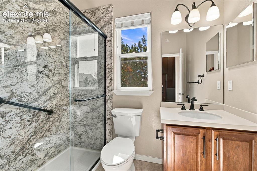 Image 28 of 48: Bathroom featuring a walk-in shower with full-height stone-patterned tile s