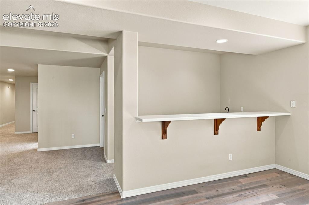 Image 32 of 48: Built-in wet bar featuring a white countertop, recessed lighting, and wood-