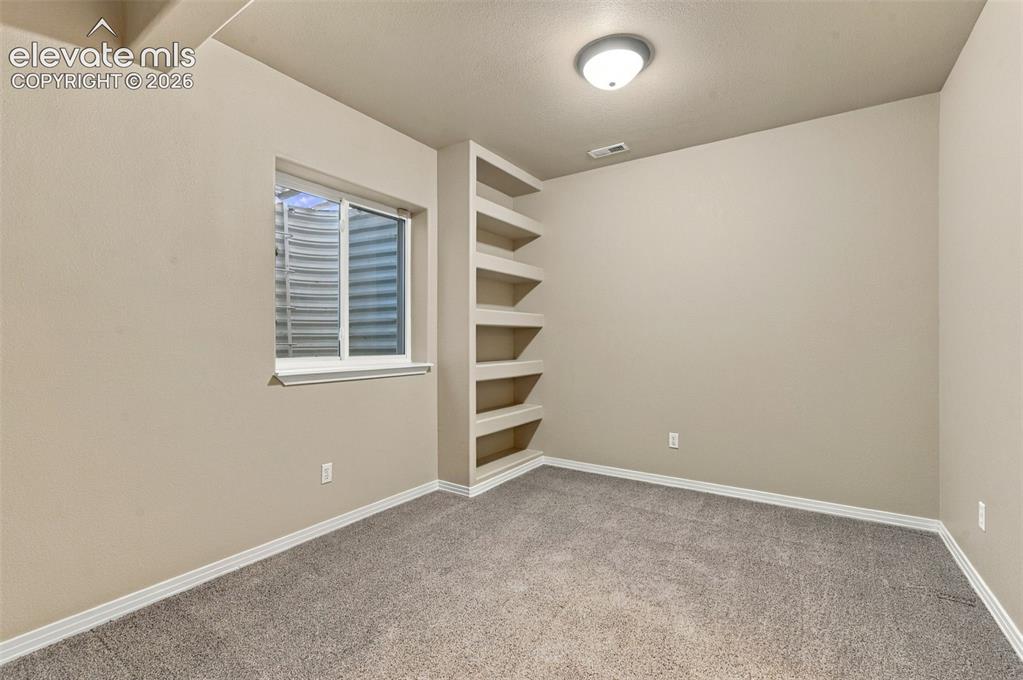 Image 38 of 48: Room featuring neutral wall-to-wall carpeting, built-in recessed shelving,
