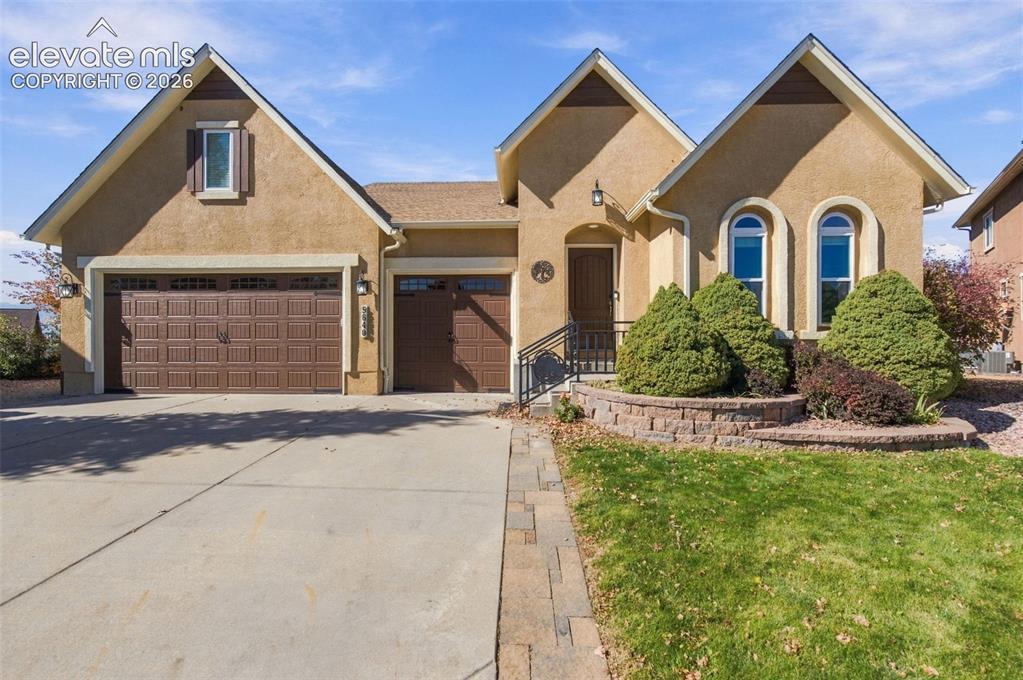 Image 4 of 48: Stucco exterior featuring multiple roof gables, a three-car garage, arched 